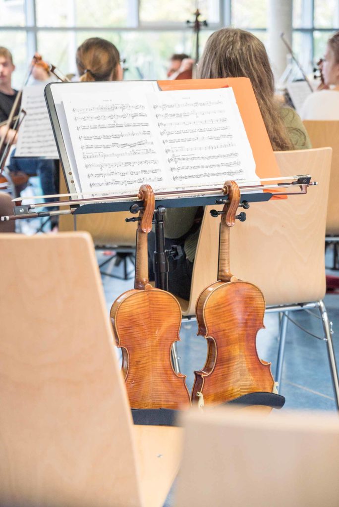 Konzertfotografie: Junge Philharmonie Würzburg Geigen hängen an Notenständer