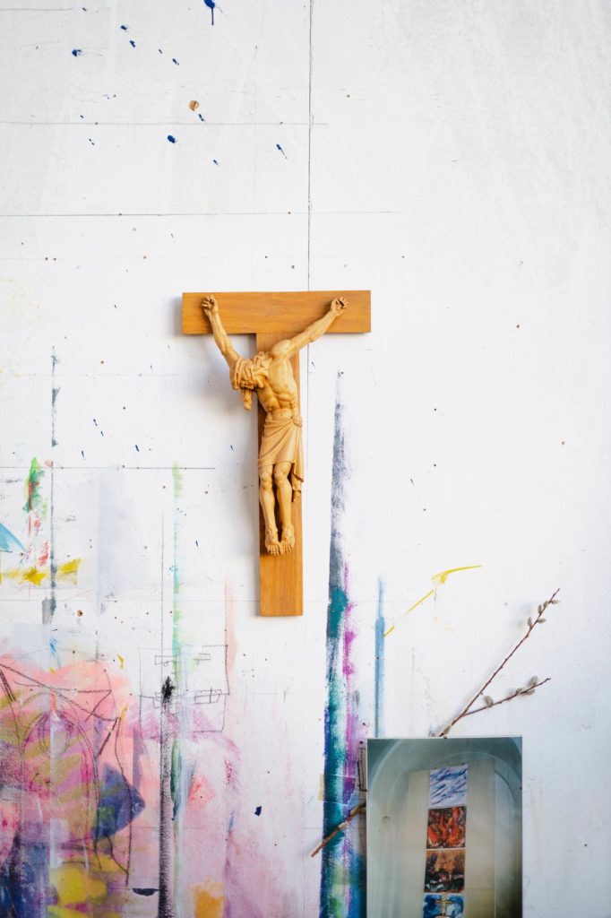 Holzkruzifix auf einer Wand mit bunten Farbklecksen