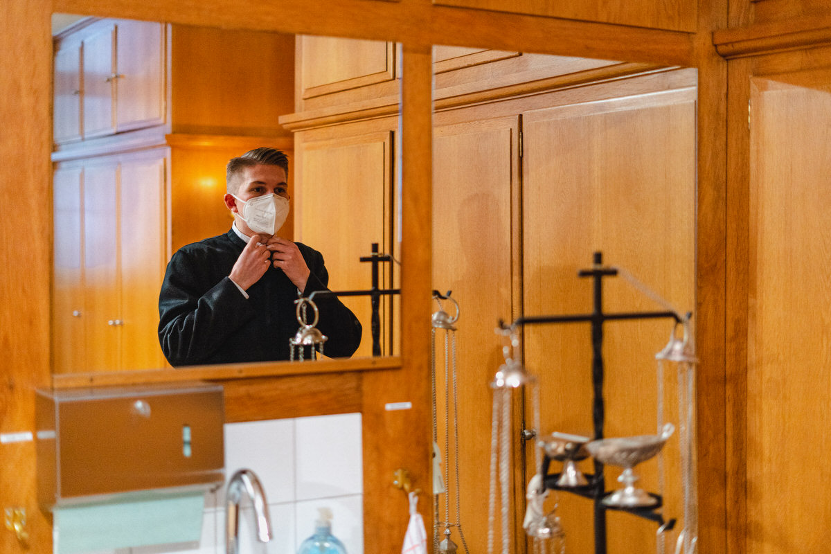 Junger Seminarist kleidet sich vor einem Spiegel für den Gottesdienst