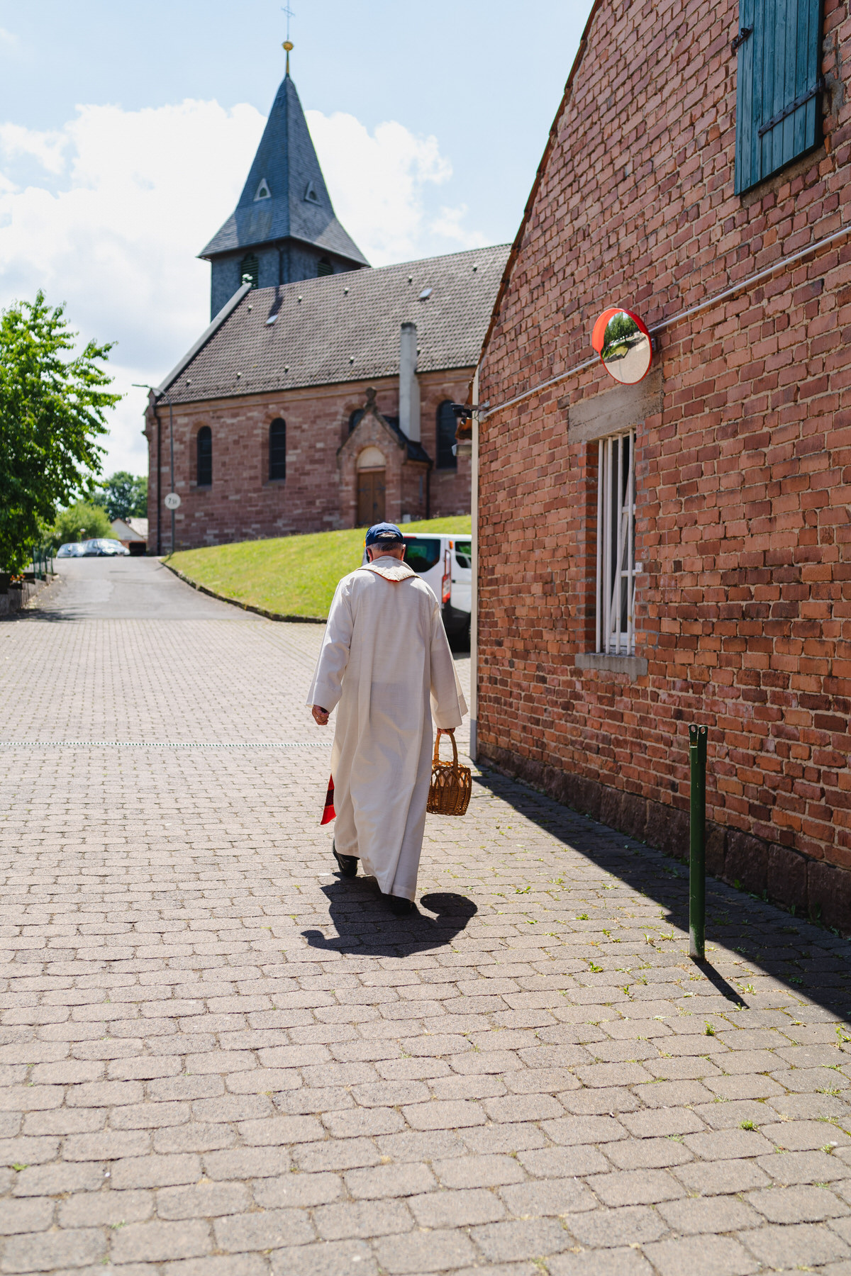 Priester mit Korb auf dem Weg zur Kirche